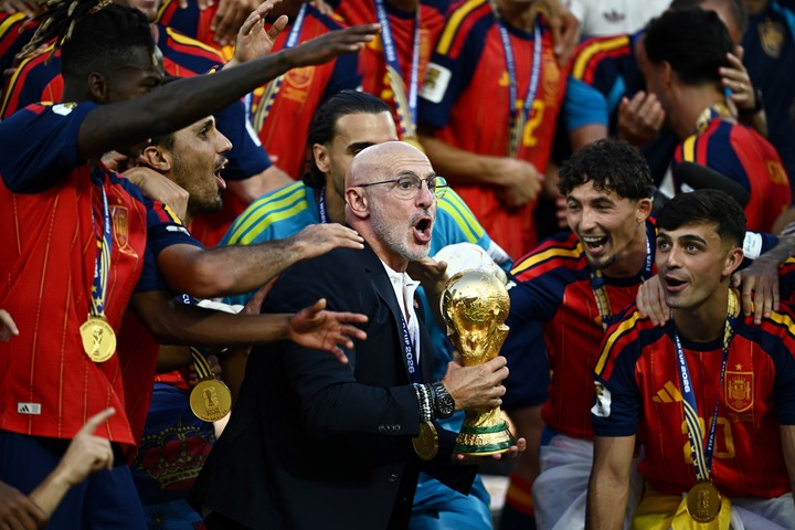 Luis de la Fuente sostiene el trofeo del Mundial junto a jugadores de la selección española durante la celebración del título.