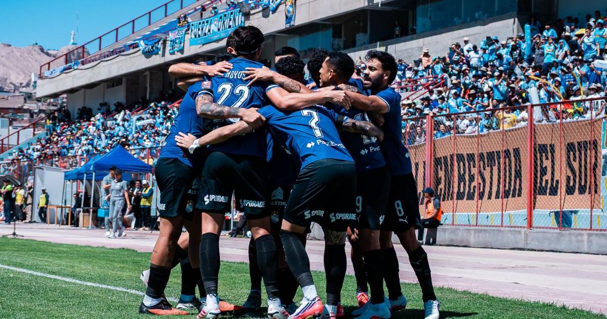 Jugadores de Sporting Cristal se abrazan en celebración sobre el campo.